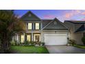 Charming two-story home featuring a manicured lawn, two-car garage, and inviting front porch at dusk at 2017 Asher Loop, Summerville, SC 29485
