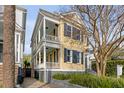 Charming yellow two-story home featuring double porches and classic architectural details in a lush setting at 49 Ashley Ave, Charleston, SC 29401