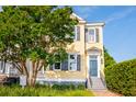 Lovely two-story yellow home with black shutters, blue door, and landscaped yard with mature tree at 49 Ashley Ave, Charleston, SC 29401