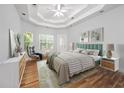 Airy bedroom showcasing tray ceilings, hardwood floors, a ceiling fan, and many windows at 3872 James Bay Road, Johns Island, SC 29455