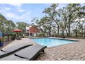 Backyard pool area with lounge chairs and a charming red home in a fenced landscaped yard at 4352 Park Island Rd, Hollywood, SC 29449