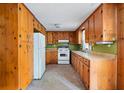 Galley kitchen featuring wooden cabinets, white appliances and neutral countertops, ready for a personal touch at 4822 Parker Dr, North Charleston, SC 29405