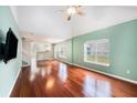 Cozy living room with hardwood floors, a ceiling fan, large windows, and a view of the kitchen at 8739 Grassy Oak Trl, North Charleston, SC 29420