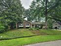 Lovely brick home surrounded by mature trees and lush greenery, showcasing a well-maintained landscape at 1389 Parkshore Dr, Charleston, SC 29407