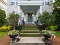 Inviting front porch with manicured bushes, flower pots, a decorative wreath, and elegant black railings at 206 White Gables Dr, Summerville, SC 29483