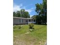 Inviting one-story home featuring a cozy front porch, green lawn, and mature trees at 215 Hines Dr, Bonneau, SC 29431