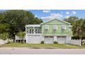 Stylish light-green home with white trim, garage, and a charming balcony, blending coastal elegance at 2218 Myrtle Ave, Sullivans Island, SC 29482