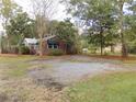 Residential property with a gravel driveway and ample outdoor parking, surrounded by mature trees at 3034 Maybank Hwy, Johns Island, SC 29455