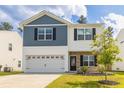 Charming two-story home featuring blue and white siding, a stone facade, and an attached two-car garage at 304 Torslanda Ln, Summerville, SC 29486