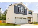 Two-story home with blue and white siding, a stone facade, a two-car garage, and a well-manicured lawn at 304 Torslanda Ln, Summerville, SC 29486