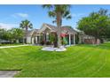 Charming brick home featuring a well-manicured lawn, palm trees, and a vibrant American flag at 7030 Billberry St, Hanahan, SC 29410