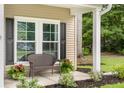 Inviting front porch features a charming bench, lovely potted plants, and a view of the landscaped front yard at 1309 Belgian Draft Dr, Mount Pleasant, SC 29466