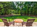 Relaxing backyard view with patio furniture, lush lawn, and mature trees offering ample shade at 1384 Tibwin Rd, McClellanville, SC 29458
