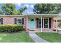 Charming brick home with a turquoise door, black shutters, and a well-manicured lawn at 1520 Kirklees Abbey Dr, Charleston, SC 29407