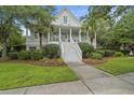 Charming two-story home with a welcoming front porch, well-manicured lawn, and lush landscaping at 228 Beresford Creek St, Charleston, SC 29492