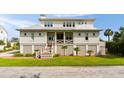 Inviting two-story beach home featuring a covered porch and manicured lawn at 2618 Raven Dr, Sullivans Island, SC 29482