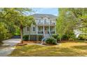 Elegant two-story home with double porches surrounded by mature trees and a well-manicured lawn at 1143 Sea Eagle Watch, Charleston, SC 29412
