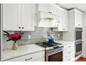 Modern kitchen with white cabinets, gray backsplash, stainless steel appliances, and quartz countertops at 51 Stocker Dr, Charleston, SC 29407