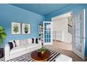 Inviting living room features a white sofa, striped rug, blue walls with white trim, and glass french doors at 5133 Park Creek Ave, North Charleston, SC 29418
