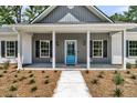 Close-up of the inviting front porch with a bright blue door, white columns, and manicured landscaping at 6513 Highway 162, Hollywood, SC 29449
