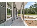 A view down the length of the front porch, showing the posts, walkway and the side yard at 6513 Highway 162, Hollywood, SC 29449