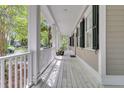 Inviting covered front porch features white railing, black shutters, and ample space for outdoor relaxation at 7021 Schooner St, Charleston, SC 29492