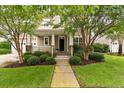 Charming home exterior with a welcoming front porch and lush landscaping with mature trees and shrubbery at 705 Quintan St, Summerville, SC 29486