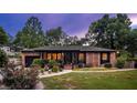 Inviting brick home with a lush front lawn and garden, enhanced by warm interior lighting and a welcoming entrance at 774 Creekside Dr, James Island, SC 29412