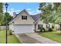 Traditional-style home with a two-car garage, manicured lawn, and mature landscaping at 104 Lancaster Ct, Goose Creek, SC 29445