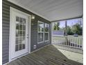 Inviting covered porch showcasing wood flooring, white railing, and a view of the surrounding neighborhood at 108 Wisteria Falls Ln, Saint Stephen, SC 29479