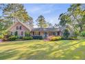 Beautiful brick home with a manicured lawn, mature trees, and a bright blue front door, creating a warm and inviting curb appeal at 110 W 2Nd South St, Summerville, SC 29483