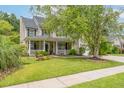 Charming two-story home with a welcoming front porch, mature trees, and well-maintained lawn at 125 Spring Meadows Dr, Summerville, SC 29485