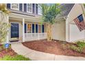 Close-up of home's front door and yard, showing mulch bed, porch, and American flag at 1253 Horseshoe Bnd, Mount Pleasant, SC 29464