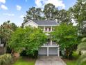 Charming two-story traditional home with a double porch and a two-car garage surrounded by lush greenery at 1417 S Jetties Ct, Mount Pleasant, SC 29466