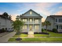 Charming two-story home with a double porch illuminated at dusk, surrounded by lush, manicured landscaping at 1485 Bourne Xing, Mount Pleasant, SC 29466