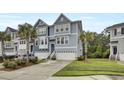 Townhome showcasing a blue exterior, two-car garage, palm trees and driveway at 1550 Spring Moss Rd, Mount Pleasant, SC 29466