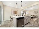 Open concept kitchen with an island, stainless steel dishwasher, wood floors, and stylish pendant lighting at 167 Surfbird Rd # 649P, Summerville, SC 29486