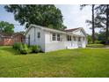 Side view of a white brick ranch-style home with a red roof, attached garage, and well-manicured lawn at 2058 Bishop Dr, Charleston, SC 29414