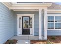 Elegant front entrance with a black door, glass panels, white trim, and stately columns at 2477 Sawlog Ln, Summerville, SC 29486