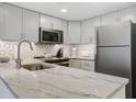 Well-lit kitchen featuring granite countertops, stainless steel appliances, and gray cabinets at 2909 Atrium Villa, 9, Seabrook Island, SC 29455