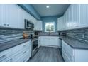 Modern kitchen boasts white cabinets, stainless steel appliances, a mosaic backsplash, and gray countertops at 4991 Lake Palmetto Ln, North Charleston, SC 29418