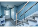 Staircase featuring gray carpet, wood trim, and modern cable railing, leading to a hallway and door at 4991 Lake Palmetto Ln, North Charleston, SC 29418