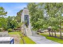 Angle view of the side of a two-story house with a front staircase and lush trees and vegetation around the lawn at 501 Joseph St, Charleston, SC 29412
