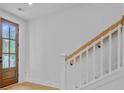 Bright hallway featuring a wooden front door, hardwood floors and the start of staircase with a white railing at 501 Joseph St, Charleston, SC 29412