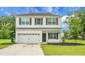 Two-story home boasts white siding, black shutters, and attached garage surrounded by lush greenery at 717 Butter Rd, Bonneau, SC 29431