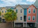 Exterior view of colorful townhomes, with covered parking and palm tree landscaping at 81 Sandbar Ln # 23, Folly Beach, SC 29439