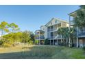 Rear view of a beautiful home featuring screened porches and a lush yard at 204 Michigan Ave # C-5 - 11, Folly Beach, SC 29439