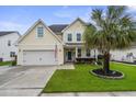 Charming two-story home featuring a well-manicured lawn, two-car garage, and a classic blue front door at 411 Topcrest Ln, Moncks Corner, SC 29461