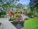 Side view of a beautiful red brick home with meticulously maintained landscaping and a three-car garage at 4272 Persimmon Woods Dr, Charleston, SC 29420