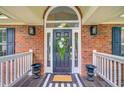 Front door entrance with a beautiful wreath, decorative lighting and planters, and a striped mat at 4272 Persimmon Woods Dr, Charleston, SC 29420